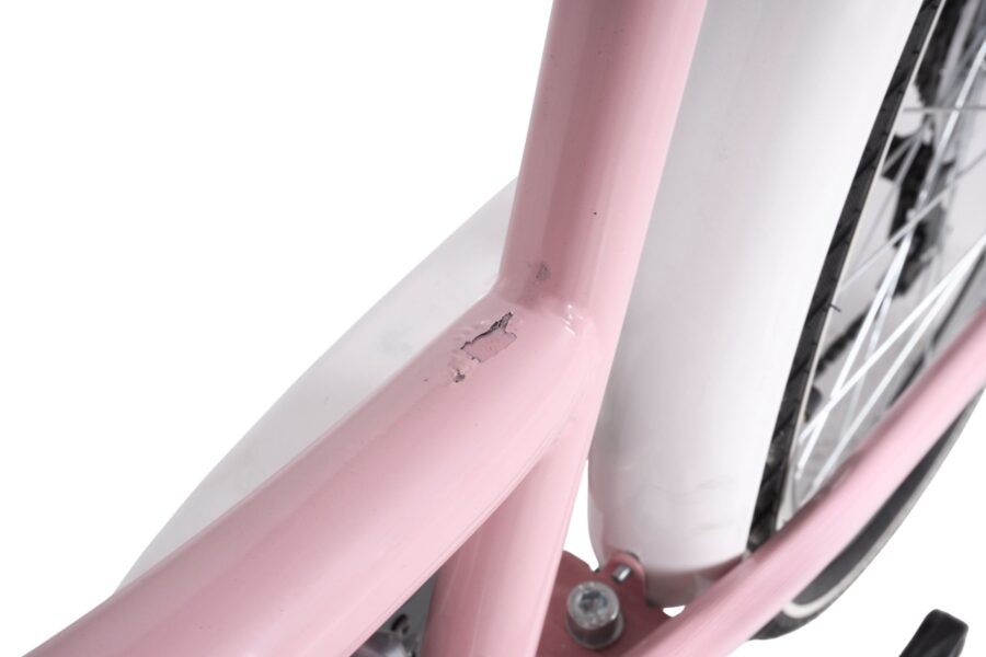 Cadru de bicicletă roz cu defecte vizibile.