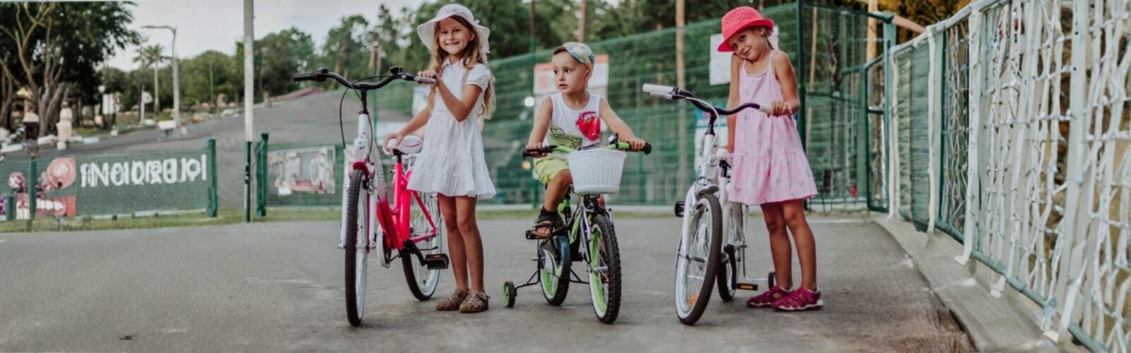 Copii pe biciclete, zâmbind pe un drum pavat.