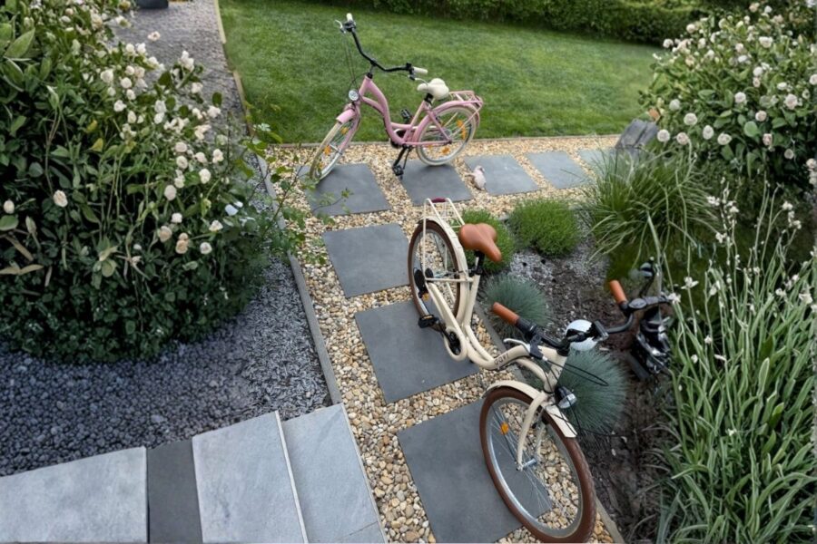 Biciclete pe alee pietruită într-o grădină verde.