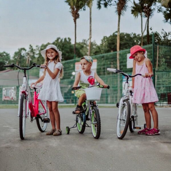 Copii fericiți pe biciclete în parc.